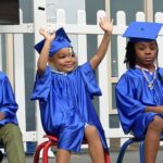 Smiling preschool children at the VOACC wearing blue graduation cap and gowns.